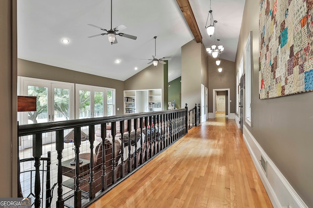 hall with wood-type flooring, beam ceiling, high vaulted ceiling, and a notable chandelier