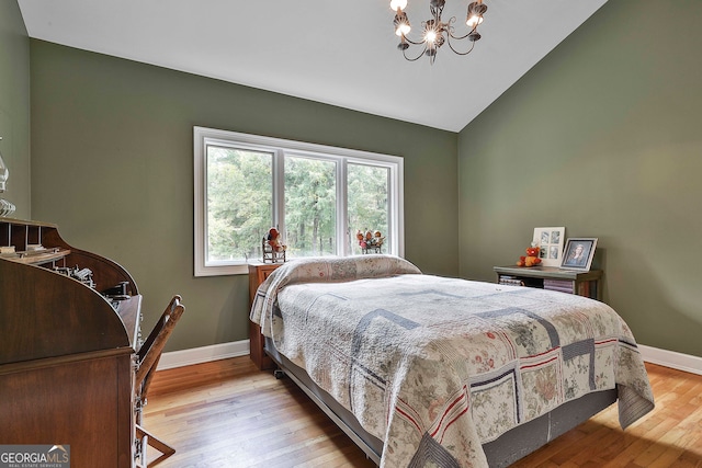 bedroom featuring an inviting chandelier, light wood-type flooring, and vaulted ceiling