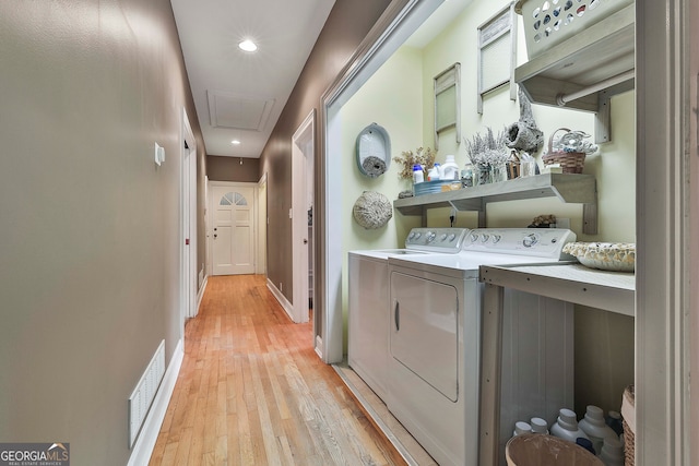 clothes washing area featuring light wood-type flooring and washer and clothes dryer