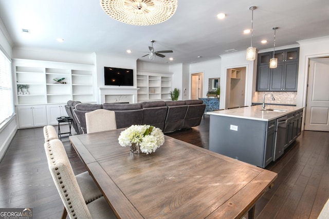 dining space featuring a premium fireplace, sink, dark wood-type flooring, and crown molding