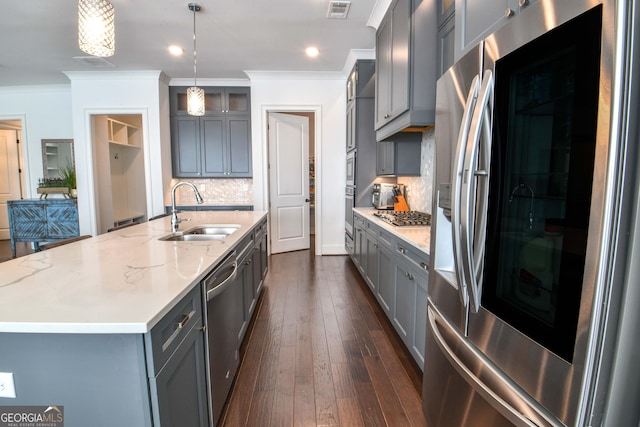 kitchen with pendant lighting, sink, appliances with stainless steel finishes, a kitchen island with sink, and gray cabinetry