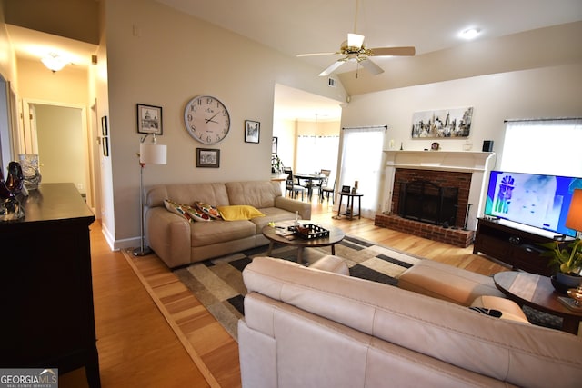 living room with light hardwood / wood-style flooring, a brick fireplace, and ceiling fan