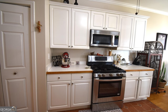 kitchen featuring dark wood-type flooring, ornamental molding, stainless steel appliances, and white cabinets