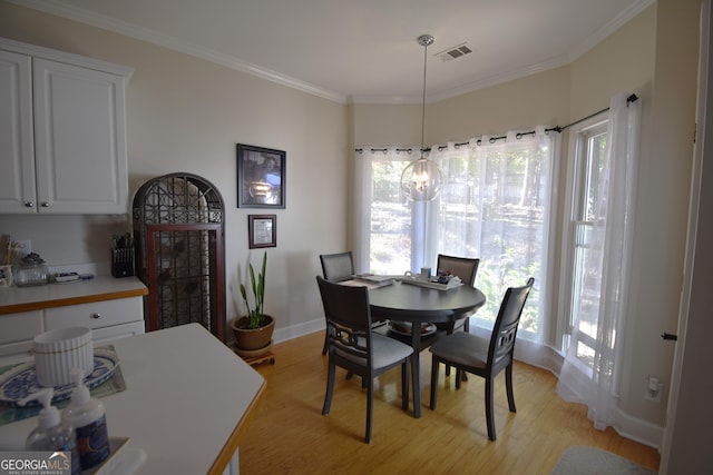 dining room featuring a chandelier, crown molding, and light wood-type flooring