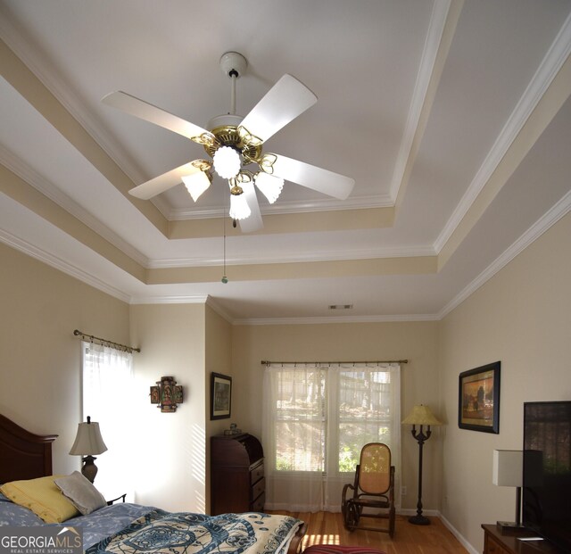 bedroom featuring ceiling fan, ornamental molding, a raised ceiling, and hardwood / wood-style floors