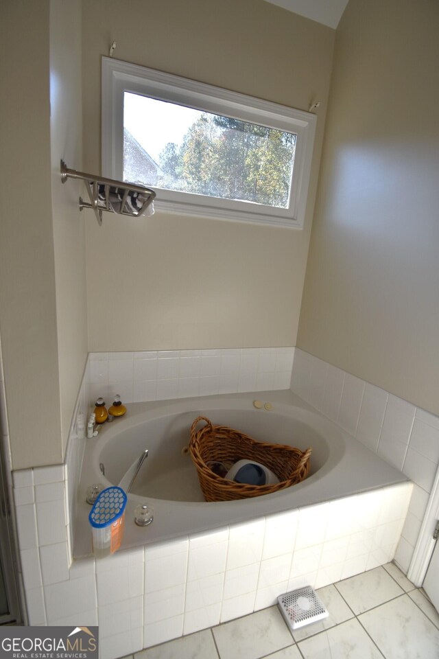 bathroom featuring a wealth of natural light, tile patterned floors, and tiled bath