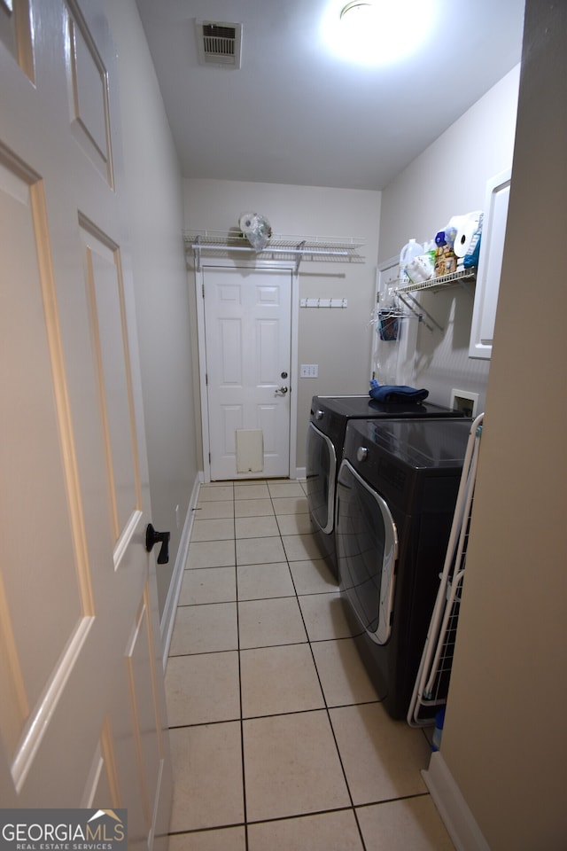 laundry area featuring washing machine and clothes dryer and light tile patterned floors