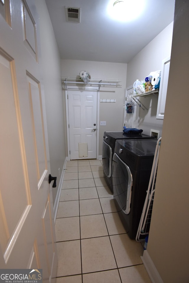 clothes washing area featuring light tile patterned floors and washing machine and dryer