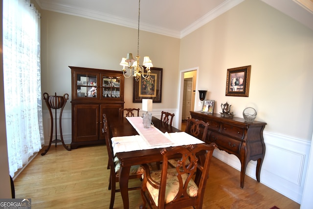 dining area with a towering ceiling, ornamental molding, light hardwood / wood-style flooring, and an inviting chandelier