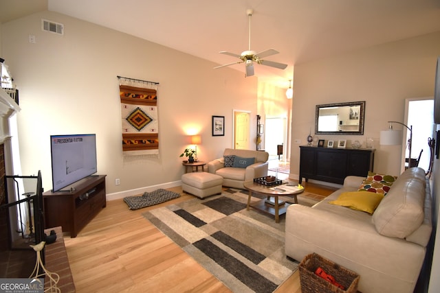 living room with vaulted ceiling, a fireplace, light wood-type flooring, and ceiling fan