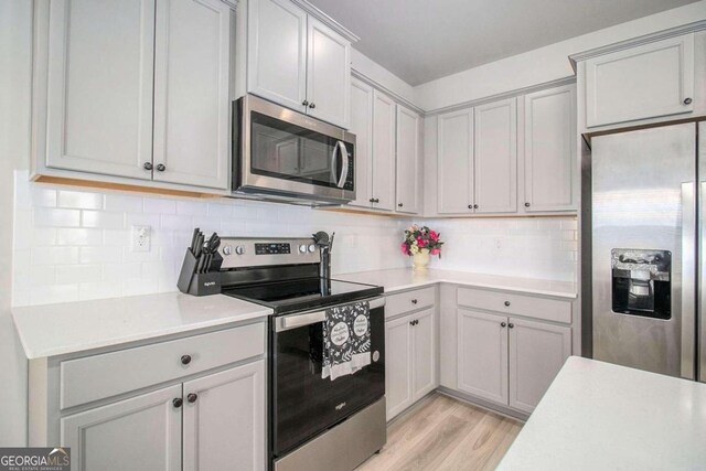 kitchen featuring appliances with stainless steel finishes, tasteful backsplash, sink, and light wood-type flooring