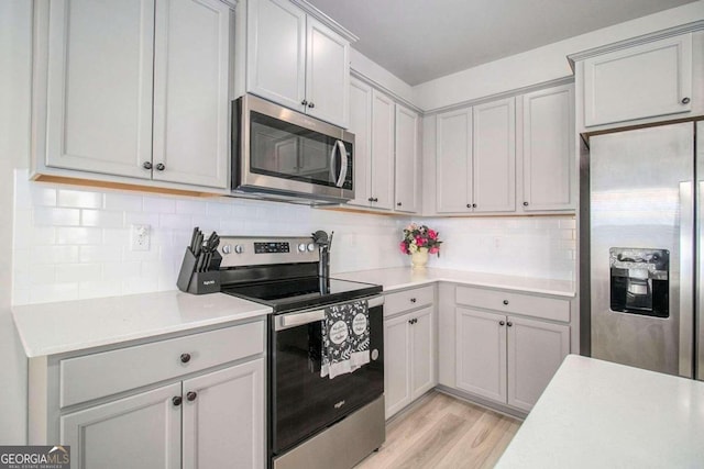 11948 Brightside Pkwy, Hampton, GA 30228 - kitchen featuring stainless steel appliances, light countertops, light wood-style floors, decorative backsplash, and gray cabinets