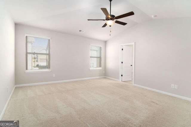 unfurnished room with plenty of natural light, light colored carpet, ceiling fan, and vaulted ceiling