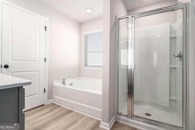 bathroom with vanity, hardwood / wood-style flooring, and shower with separate bathtub