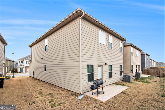 rear view of house with cooling unit, a patio area, and a lawn