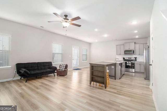 kitchen with a breakfast bar, an island with sink, sink, light hardwood / wood-style floors, and stainless steel appliances