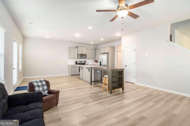 living room with ceiling fan and light wood-type flooring