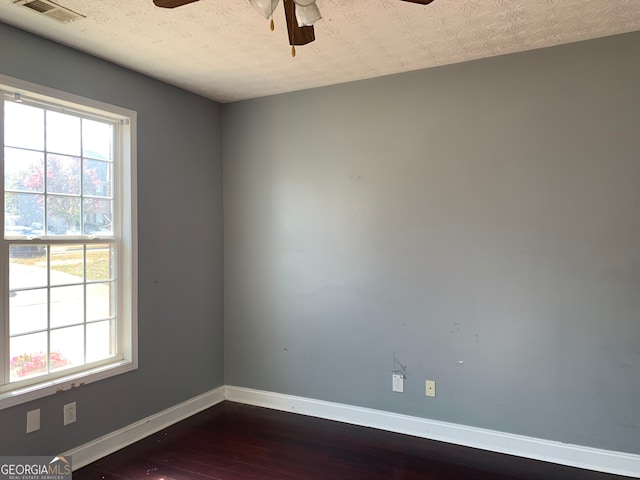 empty room featuring a textured ceiling, dark wood-type flooring, and ceiling fan