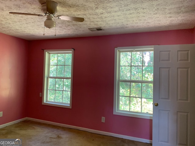 carpeted spare room with ceiling fan, a textured ceiling, and plenty of natural light