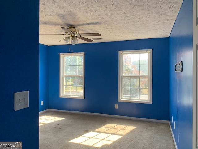 carpeted spare room with a textured ceiling and ceiling fan