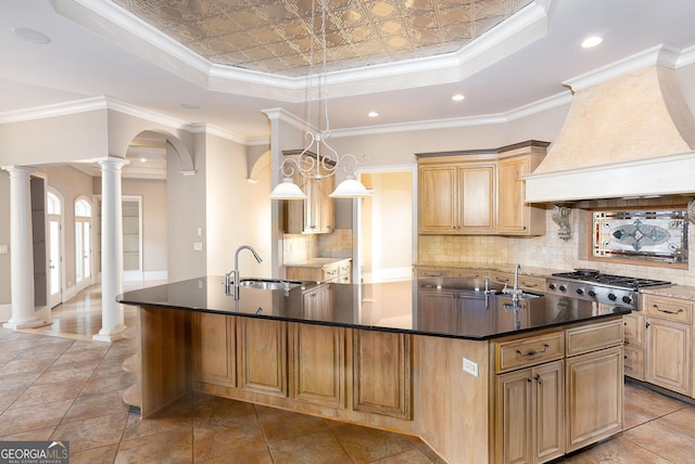 kitchen featuring a raised ceiling, stainless steel gas cooktop, a large island, a sink, and custom range hood
