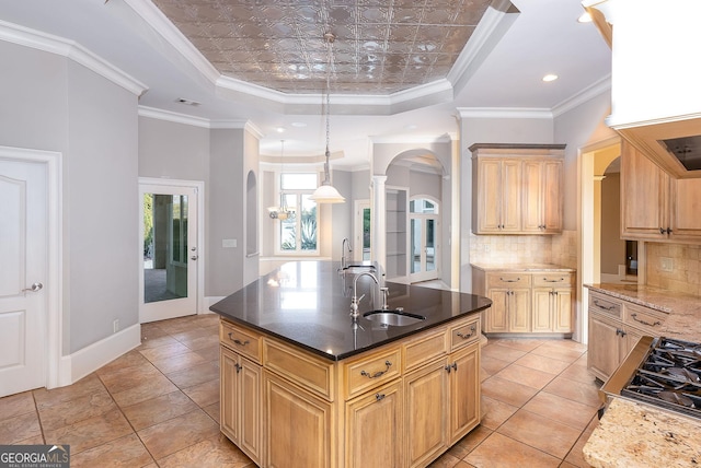kitchen with arched walkways, a raised ceiling, a sink, backsplash, and gas stovetop