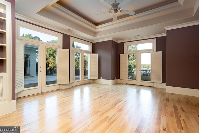 unfurnished room featuring a tray ceiling, french doors, ornamental molding, a ceiling fan, and wood finished floors