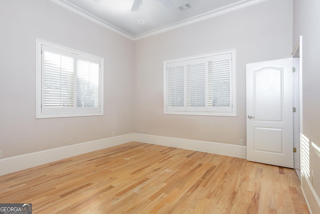 empty room featuring crown molding, light wood-style flooring, a ceiling fan, and baseboards
