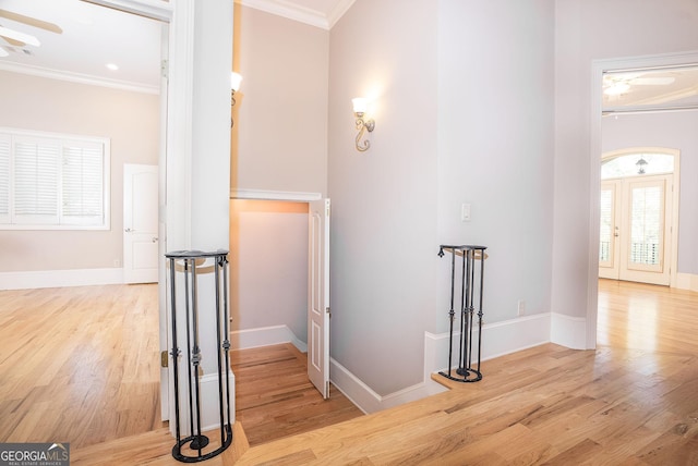 corridor with ornamental molding, light wood-style floors, and baseboards