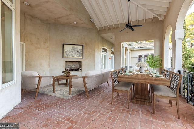 view of patio / terrace with a ceiling fan, an outdoor living space with a fireplace, and outdoor dining area