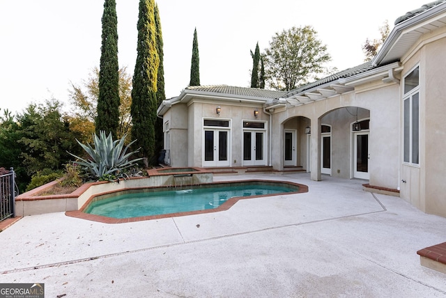 outdoor pool with french doors and a patio