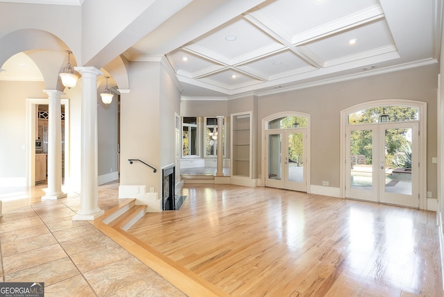 unfurnished living room featuring ornate columns, arched walkways, a high ceiling, ornamental molding, and coffered ceiling