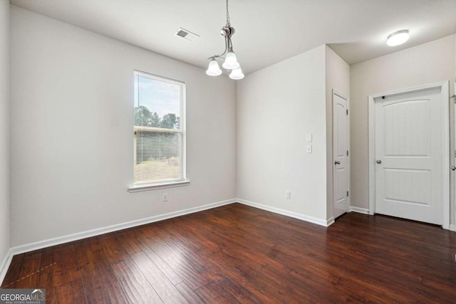 spare room featuring a chandelier and dark hardwood / wood-style floors