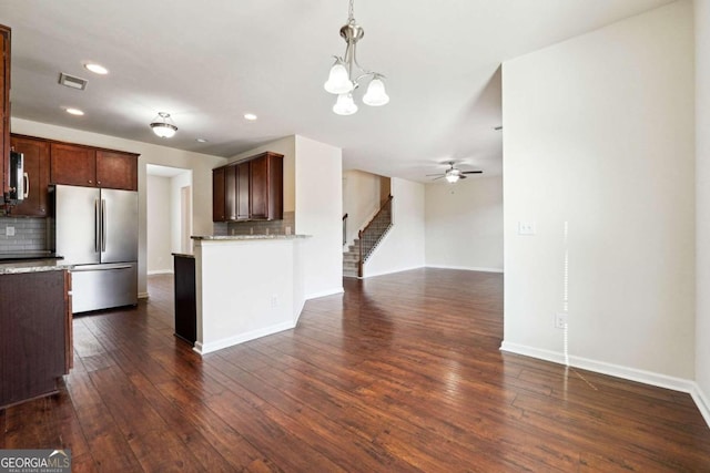 kitchen with ceiling fan with notable chandelier, stainless steel appliances, decorative light fixtures, decorative backsplash, and dark hardwood / wood-style floors