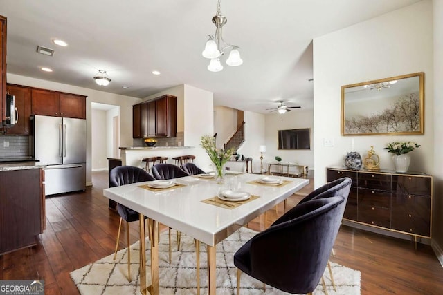 dining space featuring dark hardwood / wood-style floors and ceiling fan with notable chandelier