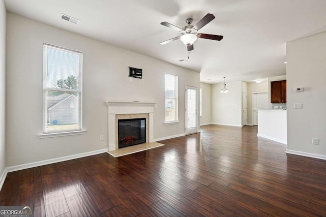 unfurnished living room with dark wood-type flooring and ceiling fan with notable chandelier