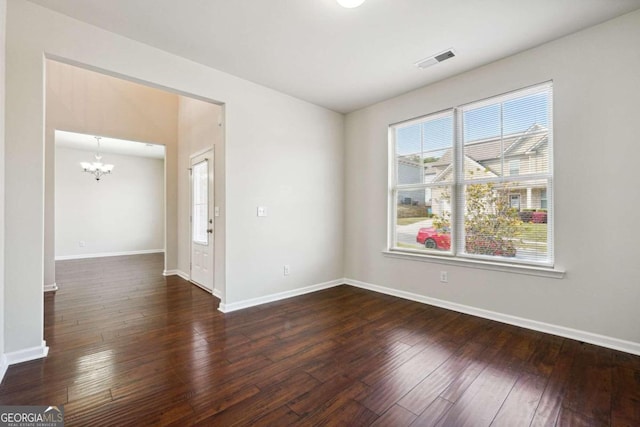 unfurnished room featuring a chandelier and dark hardwood / wood-style floors