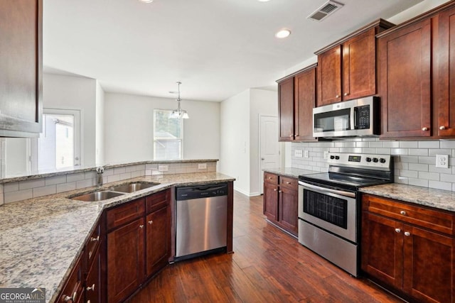 kitchen featuring sink, light stone countertops, decorative light fixtures, appliances with stainless steel finishes, and dark hardwood / wood-style flooring