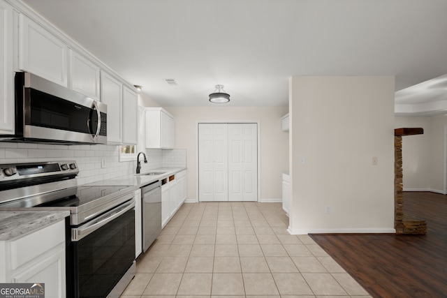 kitchen featuring sink, appliances with stainless steel finishes, white cabinetry, and light hardwood / wood-style floors