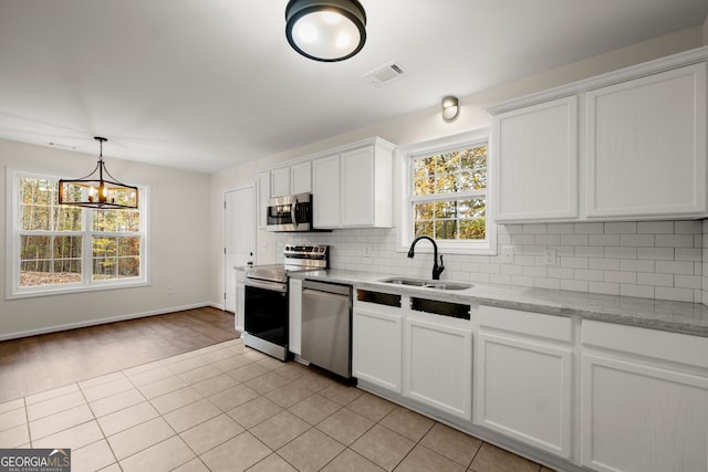 kitchen with stainless steel appliances, sink, light stone countertops, white cabinetry, and tasteful backsplash