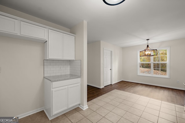 kitchen featuring white cabinetry, an inviting chandelier, light wood-type flooring, and decorative light fixtures