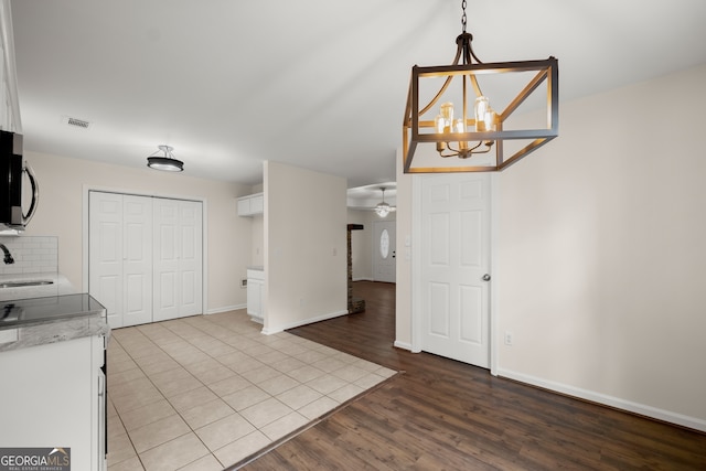 kitchen with white cabinets, tasteful backsplash, pendant lighting, light hardwood / wood-style floors, and sink