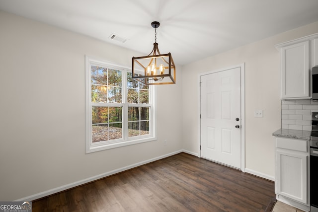 unfurnished dining area featuring a chandelier and dark hardwood / wood-style floors