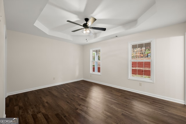 unfurnished room featuring dark hardwood / wood-style floors, a tray ceiling, and a healthy amount of sunlight