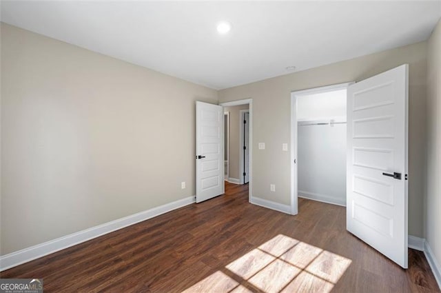 unfurnished bedroom with a walk in closet, dark wood-type flooring, and a closet