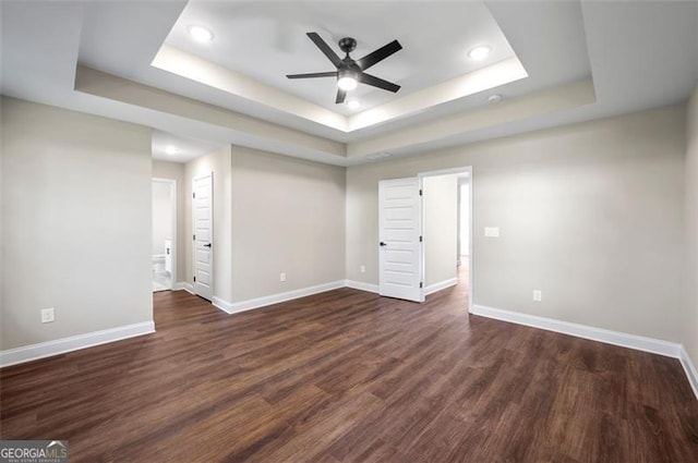 spare room with dark wood-type flooring, ceiling fan, and a tray ceiling