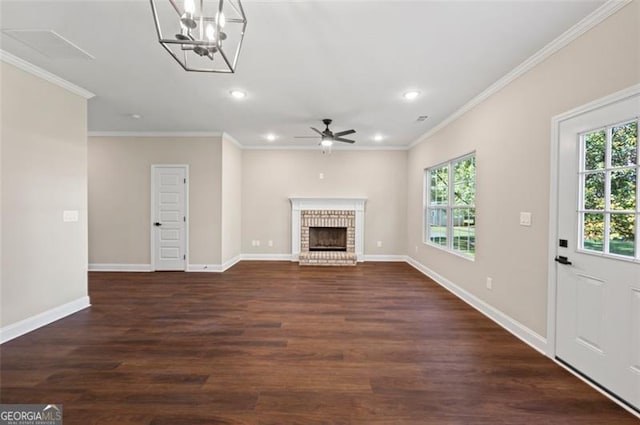 unfurnished living room featuring ornamental molding, a brick fireplace, ceiling fan with notable chandelier, and dark hardwood / wood-style flooring