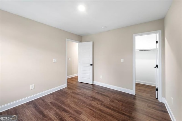 unfurnished bedroom featuring a spacious closet, dark hardwood / wood-style floors, and a closet