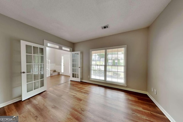 spare room with french doors, hardwood / wood-style flooring, and a textured ceiling