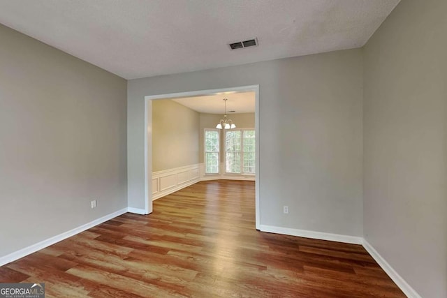 spare room with a chandelier, hardwood / wood-style flooring, and a textured ceiling